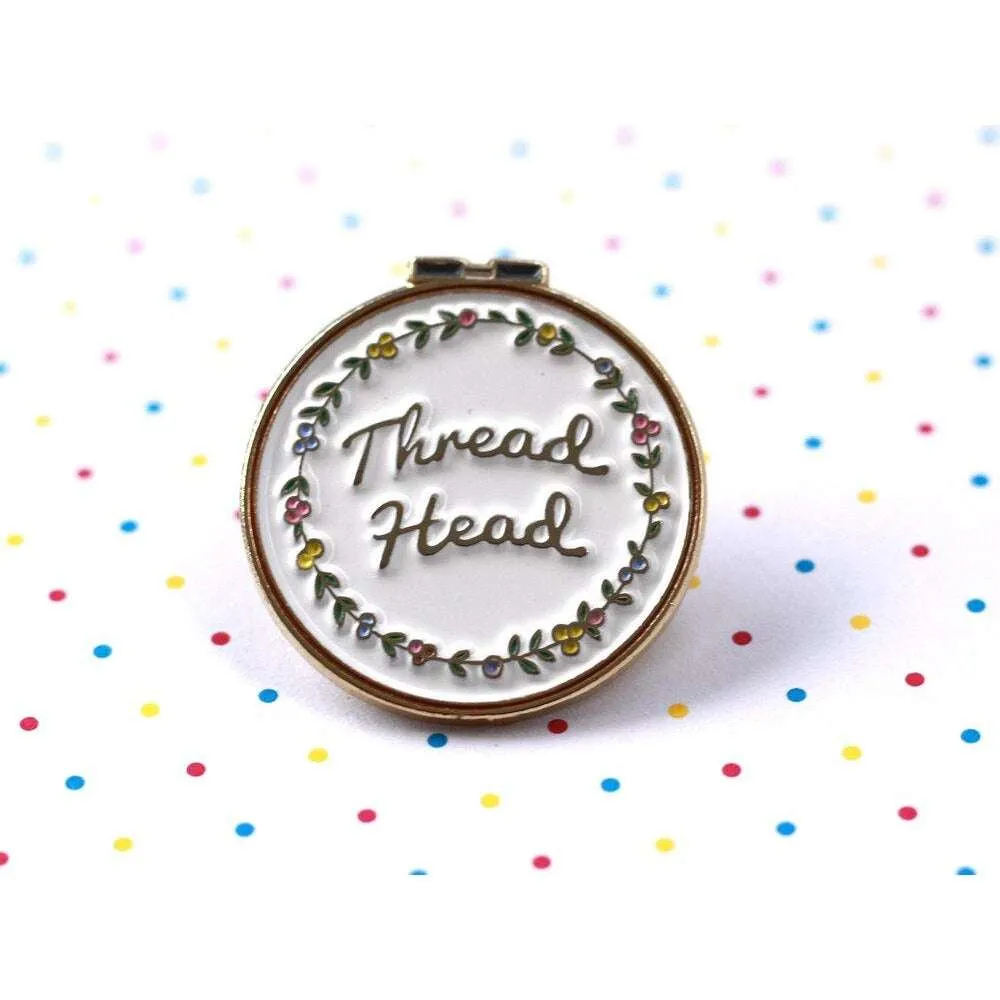 A metal circle reading 'Thread Head' in the centre surrounded by a floral design. Background is white with multi coloured polka dots